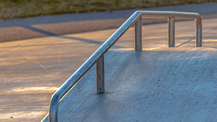 Panorama lose up of an inclined concrete ramp at a park lit by sunlight on a sunny day