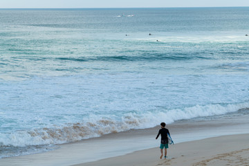 A surfer getting ready for the surf, going surfing in ocean