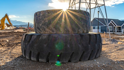 Panorama Sun in the cloudy blue sky shining brightly behind a pile of old rubber tires © Jason