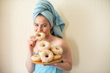 The girl in a towel has breakfast in the bed. A young attractive woman eats donuts in bed. The girl...