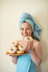 The girl in a towel has breakfast in the bed. A young attractive woman eats donuts in bed. The girl...