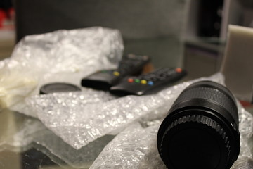 Close Up a mesa de trabajo con objetivo fotografico en primer plano sobre plastico de burbujas y...