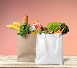 Shopping bags with fresh vegetable and groceries on desk