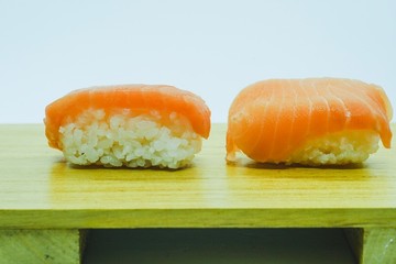 Raw Salmon Nigiri Sushi served on a wooden board against white background, a traditional japanese delicacies