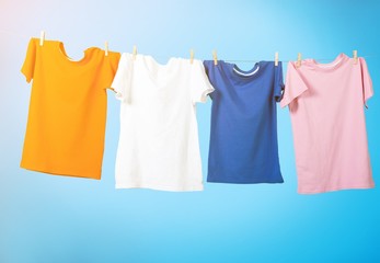 Colorful T-shirts hanging on a rope on a white background