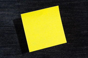 One yellow paper stickers hanging in the air (levitate) on blue jeans background