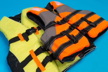two colored life jackets on a blue background, concept of saving life in water