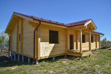 One-storey timber house with a red roof for a large family on blue sky. The construction of ecological wood homes. Mortgage, loan, dream house. Ecological material. Country private house.