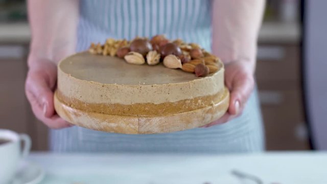 Raw nutty cake decorated with walnut, almond, macadamia and hazelnut on a blue wooden background. Healthy fresh vegan dessert. Gluten free and sugar free food