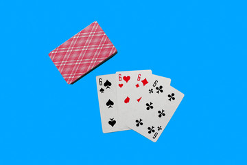Four Playing Cards Isolated on blue Background. Close-up of playing cards.Showing Six from Each...
