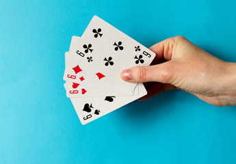 Four Playing Cards Isolated on blue Background. Close-up of playing cards.Showing Six from Each Suit - Hearts, Clubs, Spades and Diamonds. Space for text.  Playing cards isolated on blue background.