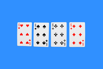 Four Playing Cards Isolated on blue Background. Close-up of playing cards.Showing Six from Each Suit - Hearts, Clubs, Spades and Diamonds. Space for text.  Playing cards isolated on blue background.