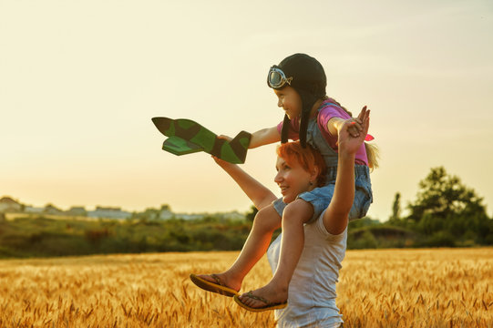 Mom and daughter playing in the field at sunset with a model aircraft . Happy family. Mother's day