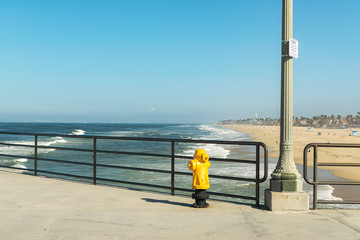 Obraz premium Yellow fire hydrant on ocean pier with clear blue skies