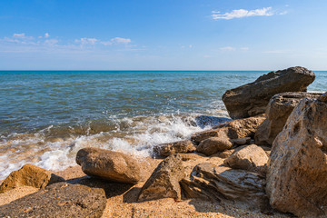 Fototapeta na wymiar Summer beach with rocks and splashing waves