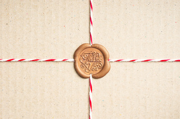 Close up of rope that tied to paper box, it's sealing with sealing wax stamp has the word pattern...