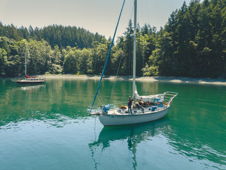 Two Sailboats Anchored at a Scenic Cove with Sailors on Deck