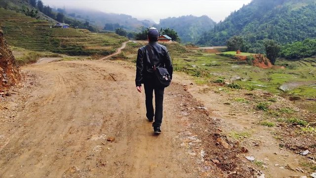 A young guy walks along the road among the rice terraces in the village of cat kat near the city of Sapa. Vietnam. 4K move drone