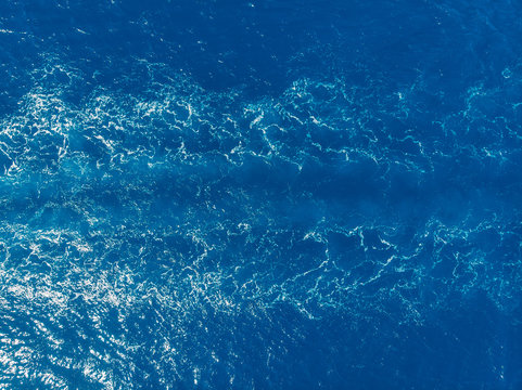 Blue sea background, waves from ship. Top view