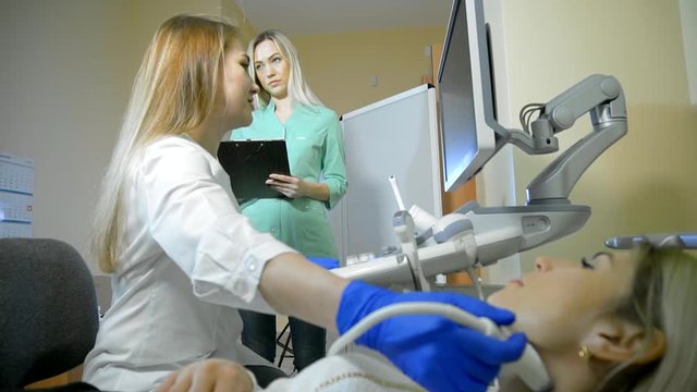 Doctor Taking A Sonogram Thyroid gland, nurse writes and helps the doctor. Camera slide and slow-mo