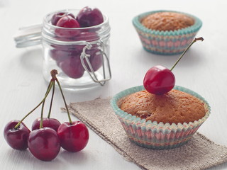 Cherry muffins upon wooden table. Fresh pastry decorated with fresh berries. Selective focus on the front.