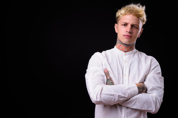 Young handsome rebellious businessman with blond hair against bl