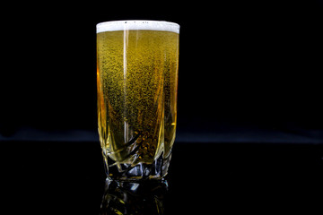 glass with beer, black background, yellow beer.