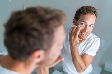 Man putting skincare facial treatment cream on face. Anti-aging skin care product. Male beauty...