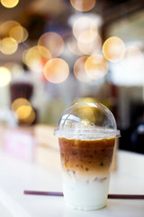 Cold coffee in plastic cup on a wooden table in cafe