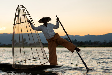 Silhouettes fisherman fishing at lake. silhouette man on boat on river sunset at Inlay Myanmar Local people asian.