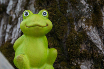 Ceramic frog statue on the background of wood bark