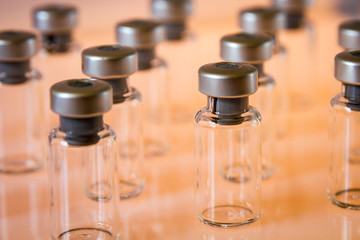 Vaccine glass bottles on orange background