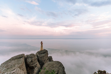 A girl in a dress and hat admiring the dawn or sunset of the sun in a picturesque place in the...