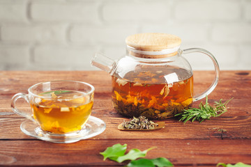 glass teapot with cup of black tea on wooden table
