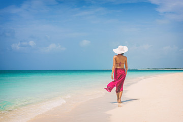 Luxury travel vacation elegant lady walking on beach in pink fashion skirt wrap relaxing on...