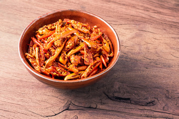 Roasted chilli in sesame oil and sprinkled with sesame seeds are used as side dishes or snack in ceramic bowl on old wooden table