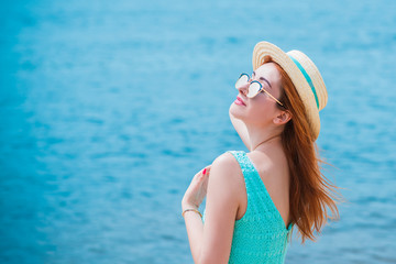 Fashionable and romantic womans look. Girl in straw hat at the beach in turquoise dress  