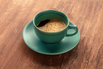 A cup of black coffee on a dark rustic wooden background
