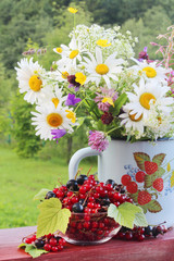 Obraz na płótnie Canvas A bouquet of wildflowers and a glass bowl of red currant 