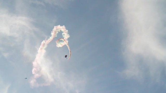 Paracadutisti si lanciano con fumogeni colorati al seguito. Esibizione aerea spettacolare.