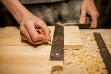 Woodwork and furniture making concept. Carpenter in the workshop marks out the details of the...