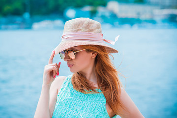 Fashionable and romantic womans look. Girl in straw hat at the beach in turquoise dress  