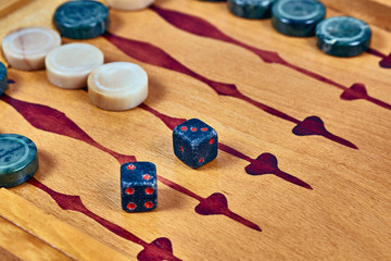 Backgammon game. Game dice made of stone lie on the backgammon board against the background of checkers. Close-up