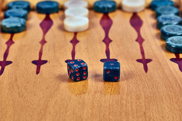 Backgammon game. Game dice made of stone lie on the backgammon board against the background of checkers. Close-up