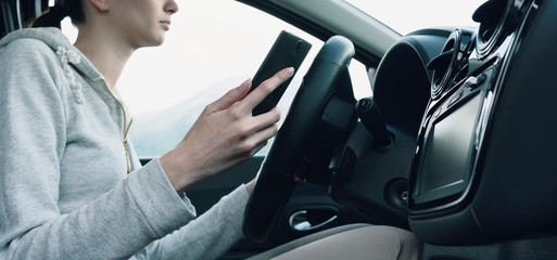 Careless woman using a smartphone in her car