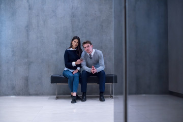 business couple using mobile phone while sitting on the bench