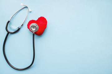 Stethoscope with red heart on pastel blue table. Doctor tool for heartbeat listening. Healthcare...