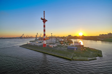 Fototapeta na wymiar Pier with mast of navigation equipment and cargo berth of ships, sunrise