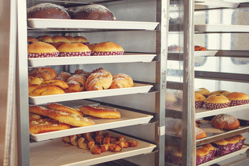 Several trays and racks of freshly baked bread and pastries at a bakery