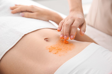 Obraz na płótnie Canvas Young woman undergoing treatment with body scrub in spa salon, closeup